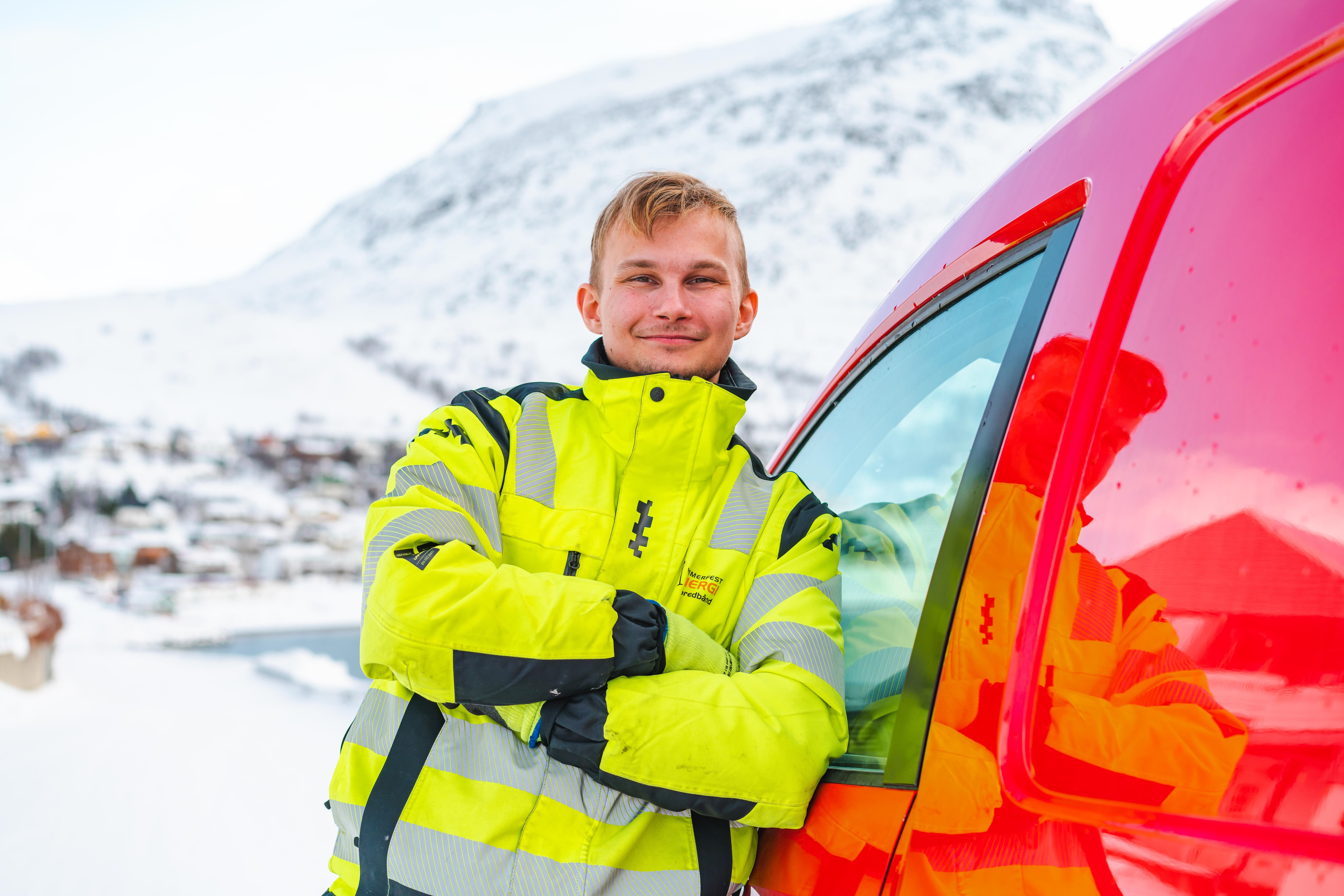 Montør smiler og lener seg mot bil hos Hammerfest Energi